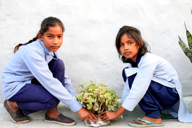 Elementary students of Indian ethnicity holding plant in hands.